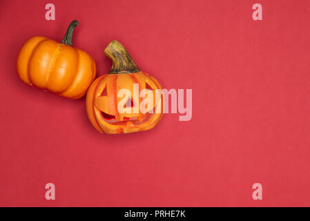 Dolcetto o scherzetto Halloween scolpita stagionali di zucca. Copia disponibile spazio su sfondo rosso Foto Stock