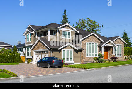 Di lusso casa residenziale con siepe verde sul lato e sul prato verde nella parte anteriore. Suburban casa familiare con doppio garage e auto parcheggiate sul viale di accesso Foto Stock