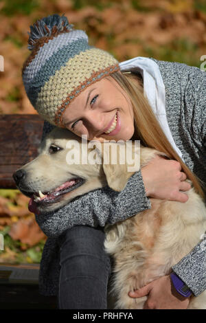 Carino, giovane sorridente ragazza bionda abbracciando il suo animale domestico, di razza golden retriever cane Foto Stock