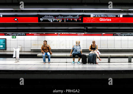 La gente seduta alla piattaforma di glorie la stazione della metropolitana di Barcellona, in Catalogna, Spagna Foto Stock