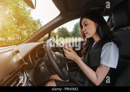 Giovane donna utilizzando uno smartphone in un auto Foto Stock