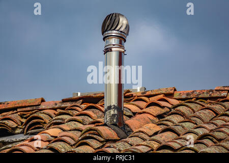 Camino di alluminio su vecchio rosso tetto di tegole Foto Stock