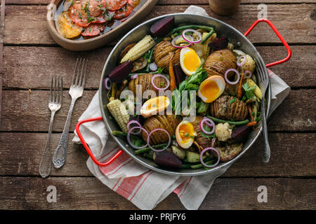 Patate Hasselback con verdure in padella Foto Stock