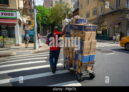 Un deliveryman da Lasership con il suo carrello carico di acquisti da personaggi del calibro di Walmart e fragrante, Amazon, e altri trudges attraverso il quartiere di Chelsea di New York sul suo nominato tornate, Mercoledì, 19 settembre 2018 . (© Richard B. Levine) Foto Stock