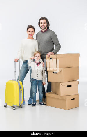 Felice ragazzo in possesso della chiave dalla nuova casa pronta a muoversi con la sua famiglia nella nuova casa isolata su bianco Foto Stock