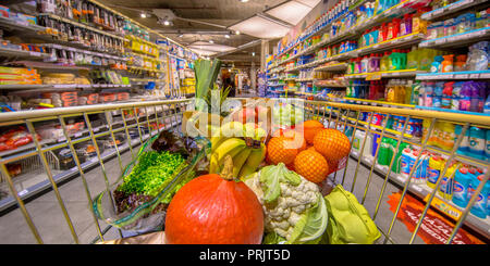 Una sana frutta e verdura in negozio di alimentari carrello nel supermercato riempiti con prodotti alimentari come visto dai clienti punto di vista Foto Stock