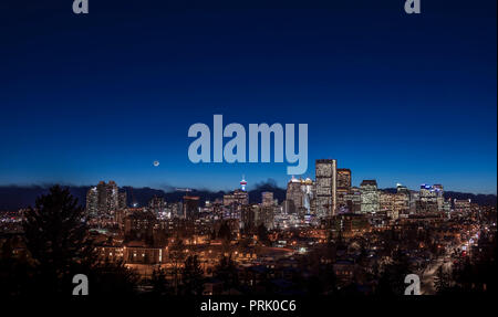 La luna crescente nello skyline di Calgary il 18 gennaio 2018. Ho girato questa da Tom Campbell Park area guardando verso sud-ovest per il tramonto twi Foto Stock