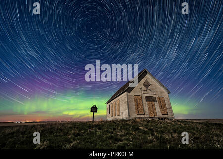 Il 1910 Liberty Schoolhouse, un classico pioneer one-room scuola, sull'Alberta prairie sotto le stelle in una notte di primavera, con stella circumpolare trail Foto Stock