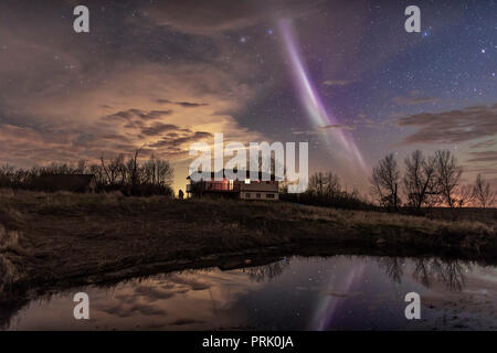 L'insolita STEVE auroral arco sopra la mia casa e riflessi nel laghetto di irrigazione nel sud Alberta, il 6 maggio 2018, su un poco nuvoloso notte. Una dim Foto Stock