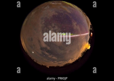 Una lente fish-eye / tutto-vista cielo dello Steve aurora arco attraverso il Cielo e nubi in maggio su 6, 2018 da casa nel sud Alberta, con una tranquilla aurora Foto Stock