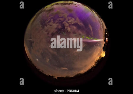 Una lente fish-eye / tutto-vista cielo dello Steve aurora arco attraverso il Cielo e nubi in maggio su 6, 2018 da casa nel sud Alberta, con una diffusa auro Foto Stock