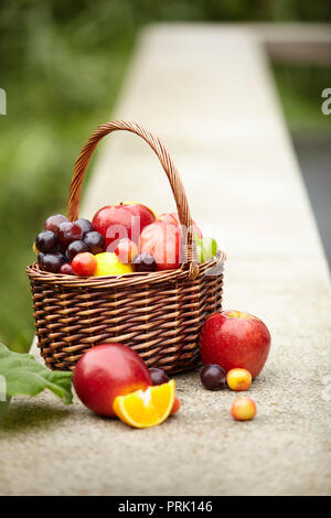 Frutti assortiti in un cesto per il picnic su una pietra esterna banco. Foto Stock