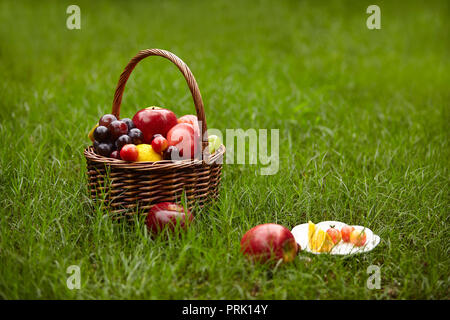Frutti assortiti in un cesto per picnic sull'erba. Foto Stock