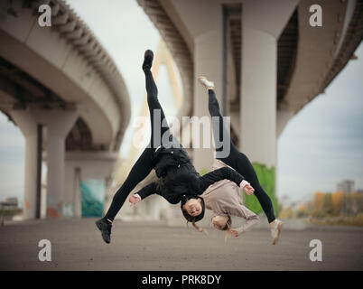 Le ragazze in modo sincrono il salto in un gruppi sul background urbano del ponte Foto Stock