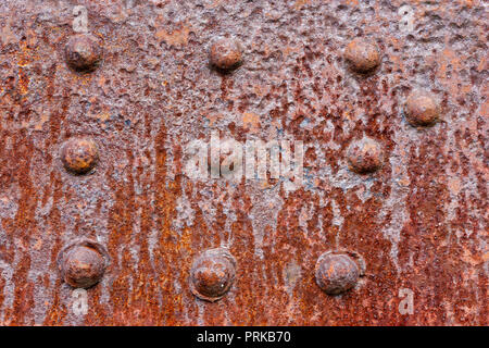 Gli sfondi e texture: metallo arrugginito la superficie di parete con chiodatura, industriale abstract Foto Stock