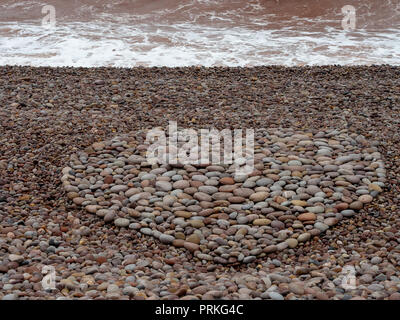 Grande amore forma di cuore realizzata con ciottoli sulla spiaggia. Foto Stock