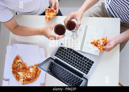 Team sorridente avente una riunione informale con la pizza Foto Stock