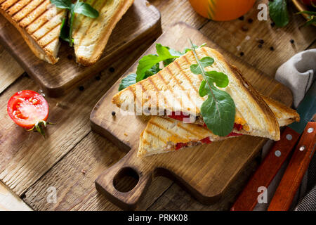 Concetto di prima colazione. Frutta e succhi freschi e deliziosi panini fatti in casa con tonno, pomodoro, formaggio su una cucina in legno tavolo. Foto Stock