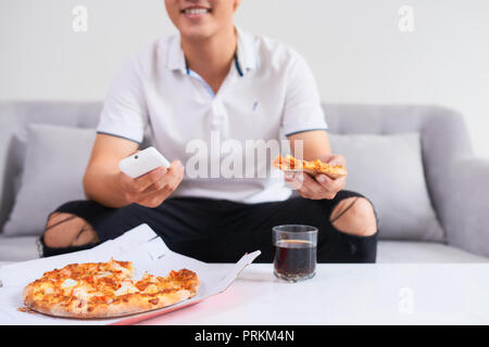 Uomo di mangiare pizza avente un takeaway a casa di riposo rilassante Foto Stock