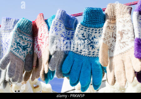 Guanti in inverno Mercatino di Natale. Una varietà colorato lavorate a maglia di lana guanti appeso a una fune. Regalo di Natale o di souvenir. Foto Stock