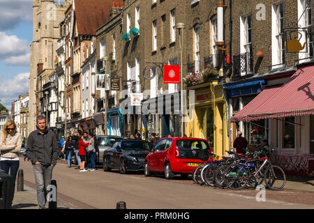 Vista di Kings Parade con negozi, edifici e persone a piedi passato su una soleggiata giornata estiva, Cambridge, Regno Unito Foto Stock