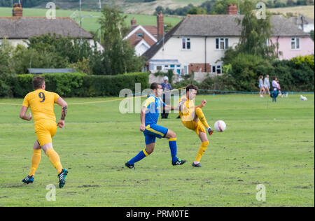 I giocatori di calcio di un pallone durante un sabato league football match con locale squadre amatoriali nel West Sussex, in Inghilterra, Regno Unito. Foto Stock