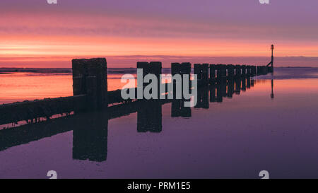 Inguine in legno sulla spiaggia di Cleethorpes, Lincolnshire presso sunrise con drammatica luce viola. Foto Stock