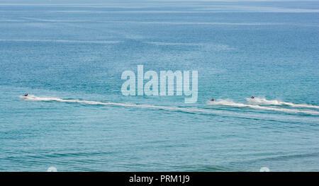 Jet Ski giostre e ingaggia a Newquay, Cornwall, getto sci visto in blu le acque del mare. Foto Stock