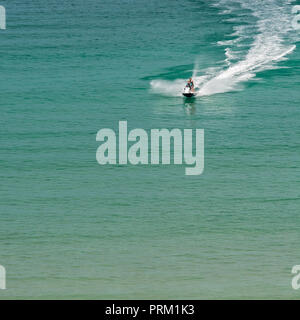 Jet Ski giostre e ingaggia a Newquay, Cornwall, getto sci visto in blu le acque del mare. Foto Stock