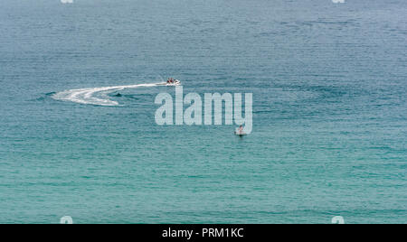 Jet Ski giostre e ingaggia a Newquay, Cornwall, getto sci visto in blu le acque del mare. Foto Stock