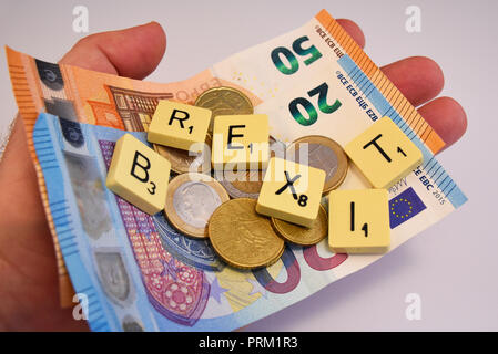 Mano con denaro contante in euro e Brexit scritte in piastrelle di Scrabble su sfondo bianco. Unione Europea voto referendario a lasciare, politica Foto Stock