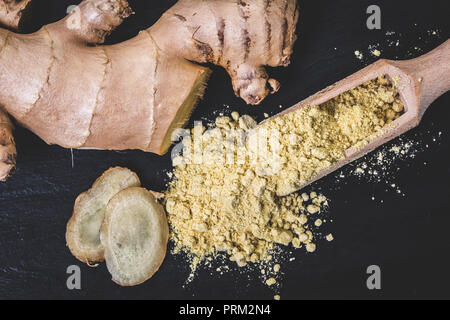 Asciugare le spezie Zenzero in un cucchiaio di legno su sfondo nero Foto Stock