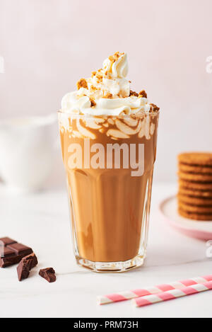 Ghiaccio di cioccolato caffè con panna montata e i cookie in un bicchiere alto con cannucce rosa bianco sul tavolo di marmo rosa su sfondo. Immagine ad alta risoluzione Foto Stock