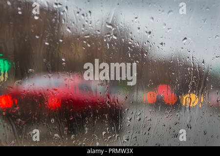 Vista della strada attraverso delle gocce di pioggia sul vetro per auto Foto Stock