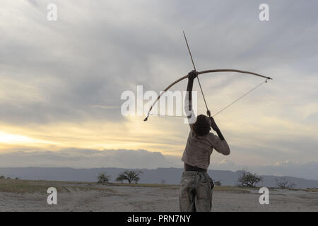 Aprile 24, 2017 - Lago Eyasi, distretto di Ngorongoro, Tanzania - poco prima che il sole tramonta dietro le colline del lontano Ngorongoro district, Osama (15) ispeziona il suo nuovo frecce e la caccia di uccelli al lago Eyasi.Gli Hadzabe sono una delle ultime opere, che rimangono nel mondo, che sopravvivono unicamente dai la caccia e la raccolta. Molto poco è cambiato nel modo in cui gli Hadzabe vivono la loro vita. Ma è diventato sempre più difficile per loro di perseguire gli Hadzabe modo di vita. Entrambi gli Hadzabe sarà trovare un modo per proteggere il loro territorio-diritti per avere accesso ad acqua depurata molle e animali selvatici o Foto Stock