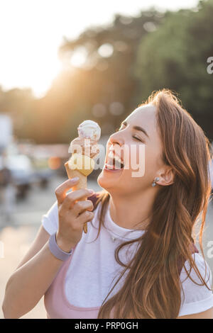 Vista ravvicinata di ridere giovane donna azienda gelato Foto Stock