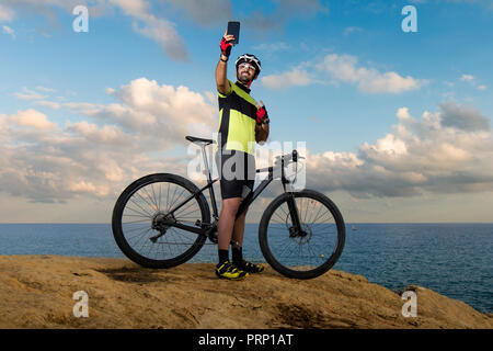 Mountain Biker prende foto sulla scogliera con segno di vittoria-spazio per il testo Foto Stock