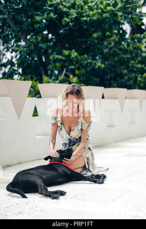 Donna bionda in abito in appoggio sulla terrazza insieme con il cane Foto Stock