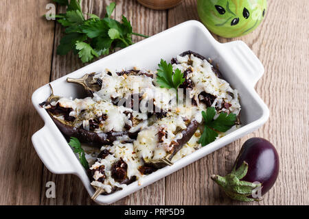 Melanzane ripiene con pomodori secchi e mozzarella in piatto di ceramica su tavola in legno rustico Foto Stock