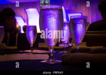 Bicchiere di acqua sudorazione con luce blu in Ristorante Foto Stock