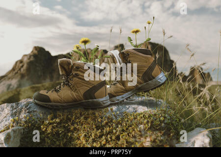 Scarpe da trekking con fiori in esso camminando sulle rocce della parte anteriore della gamma della montagna Foto Stock