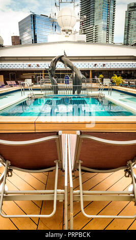 Lido Deck piscina sotto aperto Magradome apribile tettuccio. Il Volendam, Holland America R Classe nave da crociera. Ormeggiata al Porto di Vancouver, British Columbia, Canada. Il centro di Vancouver edifici in background. Foto Stock