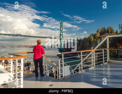 La nave di crociera i passeggeri sul ponte superiore della Holland America la Volendam, come passa sotto il Ponte Lions Gate in ingresso Burrard, Vancouver, British Columbia, Canada lungo il tragitto per l'Alaska, Stati Uniti d'America. Foto Stock