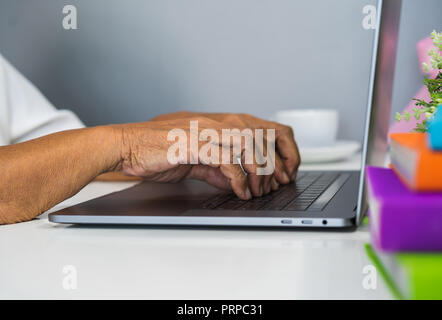 Vecchio mani femminili digitando sulla tastiera del notebook Foto Stock