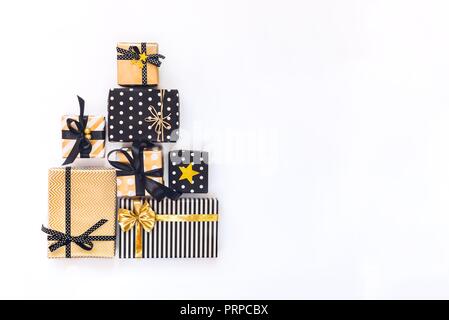 Vista superiore delle confezioni regalo in vari nero, bianco e golden disegni disposti in forma triangolare come albero di Natale o la torta di compleanno. Un concetto di Chri Foto Stock