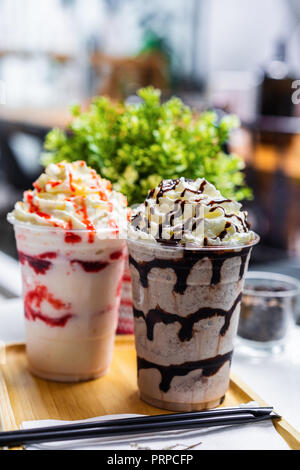 Cioccolato e fragola frappe con panna montata su tavolo Foto Stock