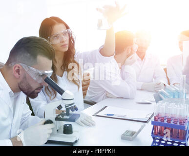 Gli scienziati di esaminare attentamente la pipetta con fluido blu in laboratorio..foto con spazio di copia Foto Stock