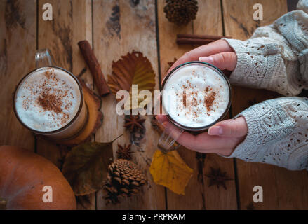 Mani pumpkin spice latte nella tazza di vetro, su sfondo di legno, vista dall'alto Foto Stock