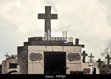 Gli oggetti contrassegnati per la rimozione definitiva nel cimitero contro il cielo nuvoloso Foto Stock