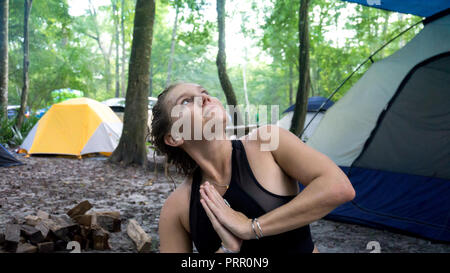 Ritratto di giovane donna facendo namaste mani pregando pongono e guardando il cielo mentre facendo yoga in vacanza in campeggio Foto Stock